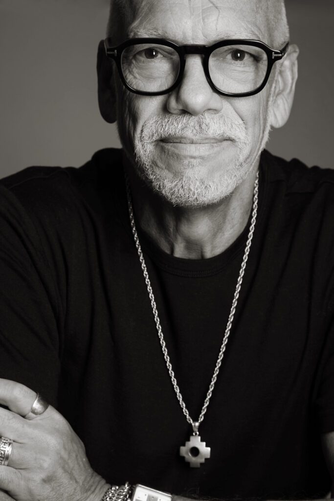 Waterloo musician headshot: older man in glasses and a black tee with a silver chain, in black and white